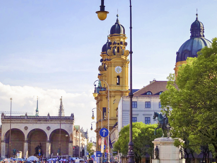 Odeonsplatz in München mit Theatinerkirche und Brunnen, sonniges Wetter.