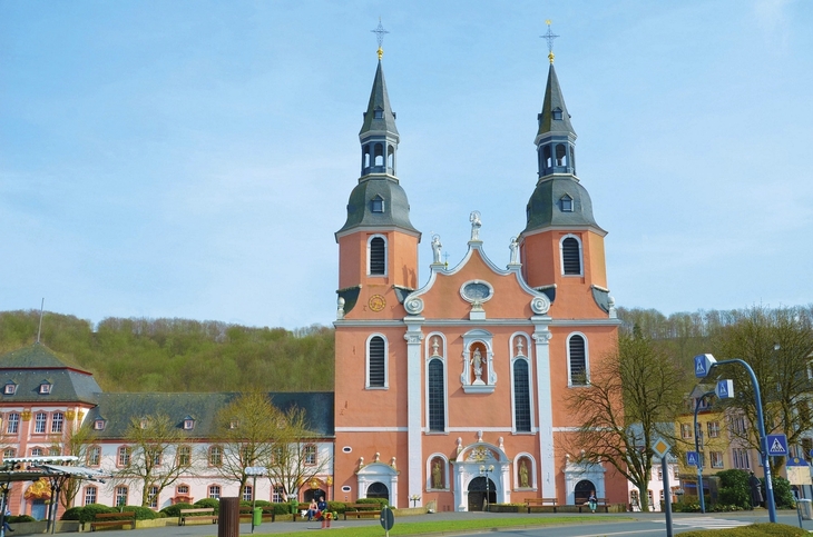 Basilika in Prüm mit zwei Türmen und barocker Fassade bei blauem Himmel.