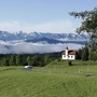 Kapelle auf Hügel vor Wolken und Bergen im Frühling.