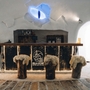 Innenansicht einer Schneebar im Iglu-Dorf mit Holzhockern und Theke.