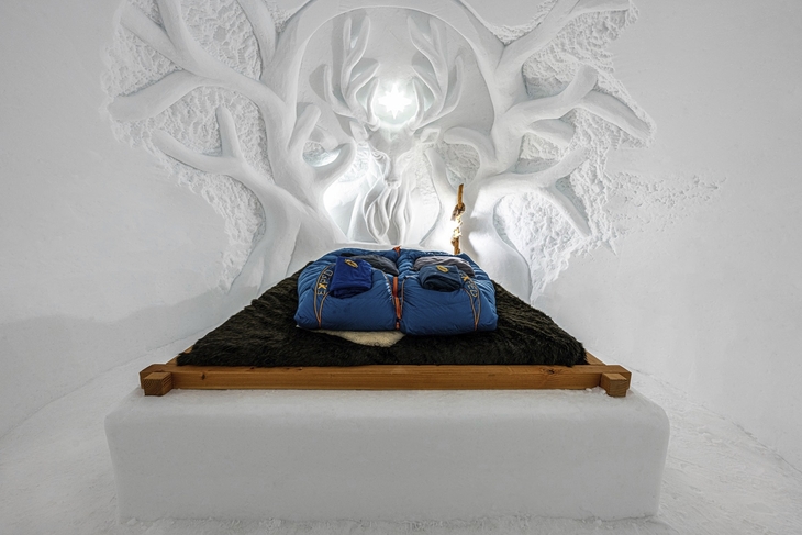 Eisige Iglu-Schlafkammer mit Dekoration und Schlafsäcken auf einem Bett.