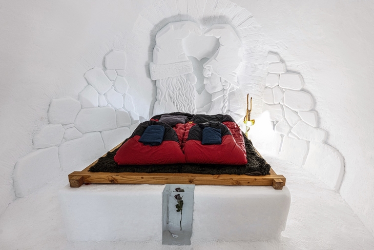 Bett in einem romantisch dekorierten Iglu mit Schnitzerei an der Wand.