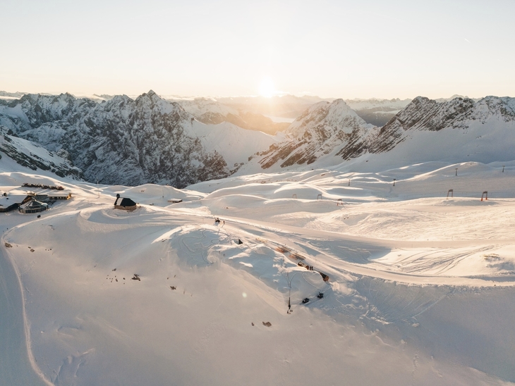 Verschneite Alpenlandschaft mit Iglu-Dorf bei Sonnenaufgang.