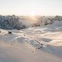 Verschneite Alpenlandschaft mit Iglu-Dorf bei Sonnenaufgang.
