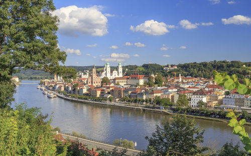 Ansicht von Linz mit der Donau im Vordergrund und Gebäuden im Hintergrund.
