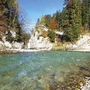 Klarer Fluss in einer herbstlichen Schlucht mit buntem Laub und Felsen.