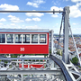 Rotes Riesenrad-Gondel überblickt Stadtlandschaft mit blauem Himmel.