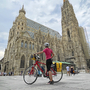 Radfahrerin mit Helm vor dem Wiener Stephansdom.