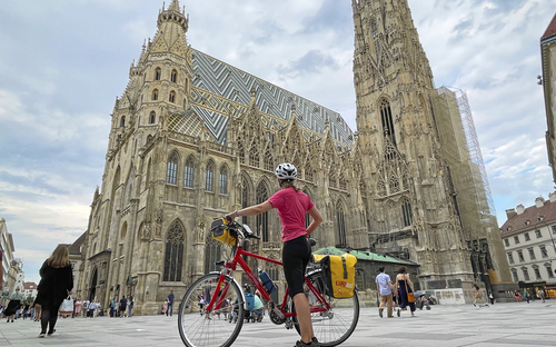 Radfahrerin mit Helm vor dem Wiener Stephansdom.