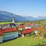 Blick über Reit im Winkl auf eine Alpenlandschaft mit Dorfkirche und Bergen im Hintergrund