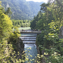 Aussicht auf den Lechfall mit Wanderern auf einer Brücke, umgeben von Wald und Bergen.