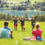 Familie rastet auf Wiese mit See im Hintergrund im Salzkammergut.