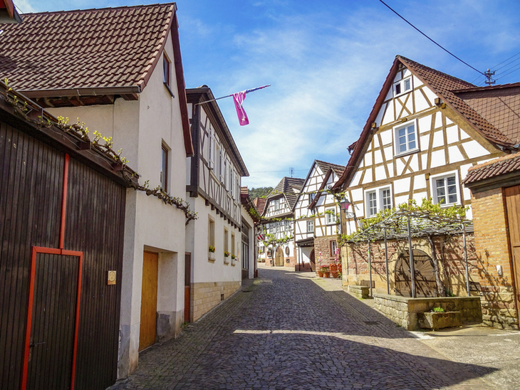 Enge Gasse mit Fachwerkhäusern unter blauem Himmel.
