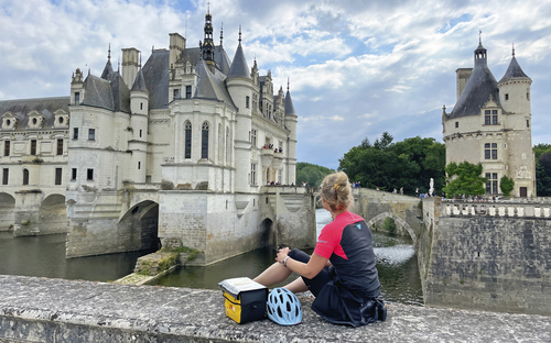 Radfahrerin blickt auf Schloss Chenonceau an der Loire in Frankreich.