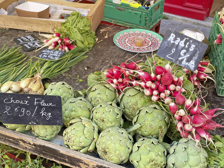 Frisches Gemüse auf einem Marktstand, darunter Radieschen und Artischocken.