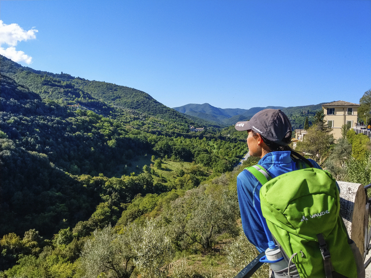 Wanderer genießt den Ausblick über grüne Hügel und Täler in Umbrien.