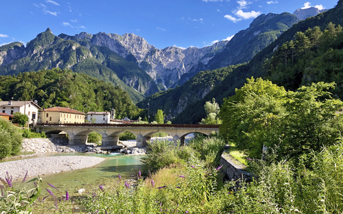 Bergpanorama der julischen Alpen mit Brücke und Fluss im Vordergrund.