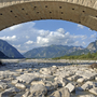 Steinbrücke über Fluss mit Bergkulisse im Hintergrund