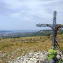 Kreuz und Rucksack mit Blick auf Küstenlandschaft und Meer im Friaul, Italien.