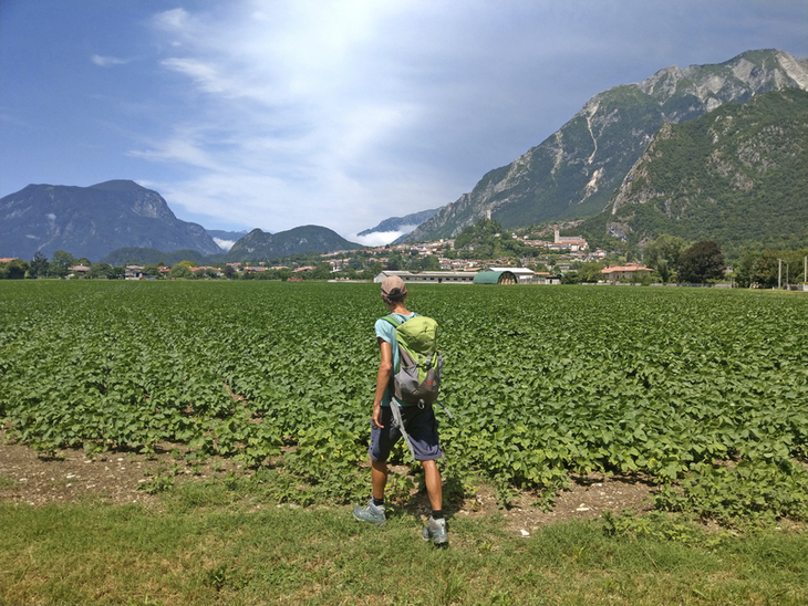 Wanderer mit Rucksack auf einem Feld vor den Julischen Alpen in Friaul.