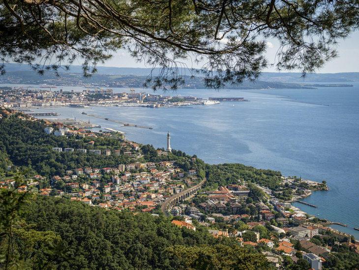 Blick auf die Küste von Triest und den Golf von Triest mit einer Stadt im Hintergrund.