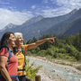 Zwei Wanderer am Flussufer in den Julischen Alpen, eine Person zeigt in die Ferne.