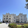 Schloss Miramare im Park bei sonnigem Wetter mit Besuchern im Vordergrund.