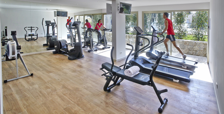 Fitnessstudio mit Laufbändern und Trainingsgeräten, Person auf Laufband.