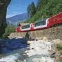 Roter Zug des Glacier Express in malerischer Berglandschaft mit Bach.