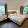 Renovierter Schlafraum mit Doppelbett und zwei Fenstern.