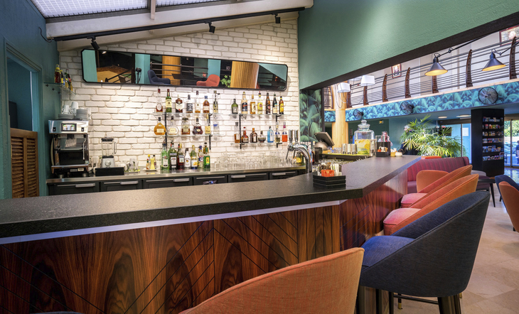 Moderne Hotelbar mit bunten Stühlen und einer großen Auswahl an Spirituosen.