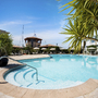 Poolbereich eines Hotels mit Liegestühlen und Palmen bei sonnigem Wetter.
