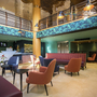 Modernes Hotel-Lobby mit bunten Sesseln, Empfangstresen und Pflanzen.