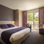 Hotelzimmer mit Doppelbett, Balkon und moderner Einrichtung.