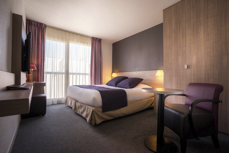 Hotelzimmer mit zwei Einzelbetten, moderner Einrichtung und Fenster ohne Balkon.