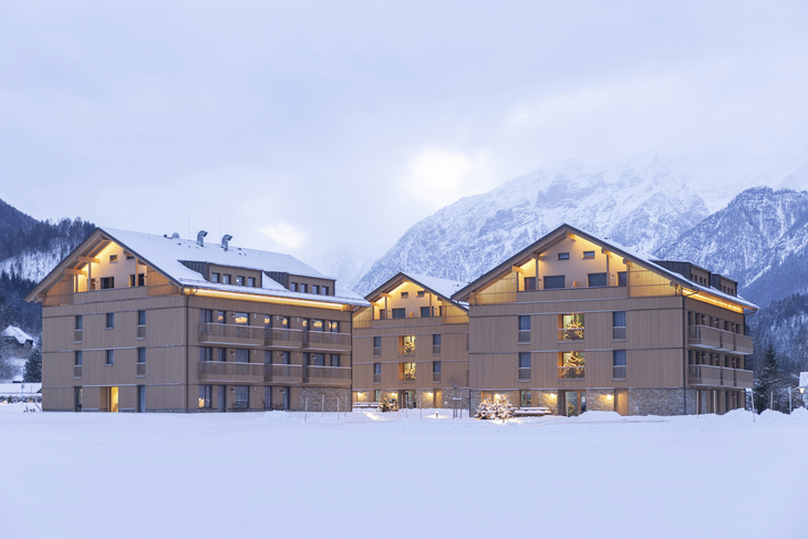Aparthotel im Winter mit schneebedeckten Bergen im Hintergrund.