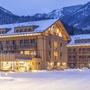 Verschneites Aparthotel in Berglandschaft bei Abenddämmerung.