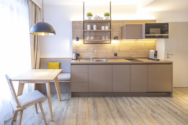 Moderne Küchenzeile mit Holztisch, Stühlen und Fenster.