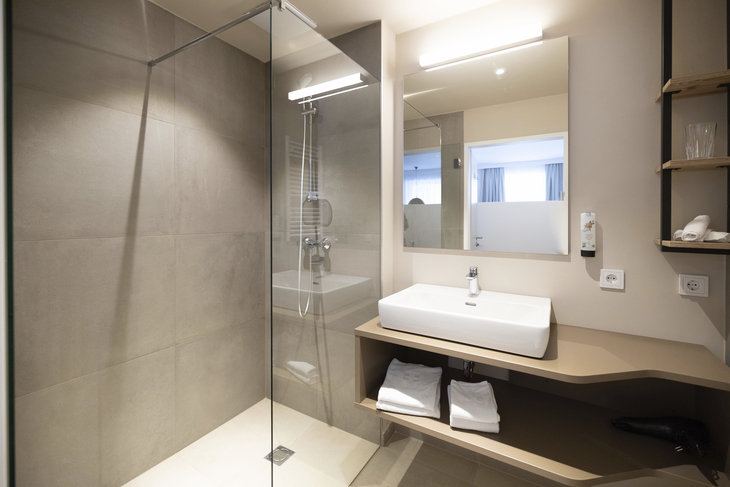 Modernes Badezimmer mit Dusche, Waschbecken und Spiegel.