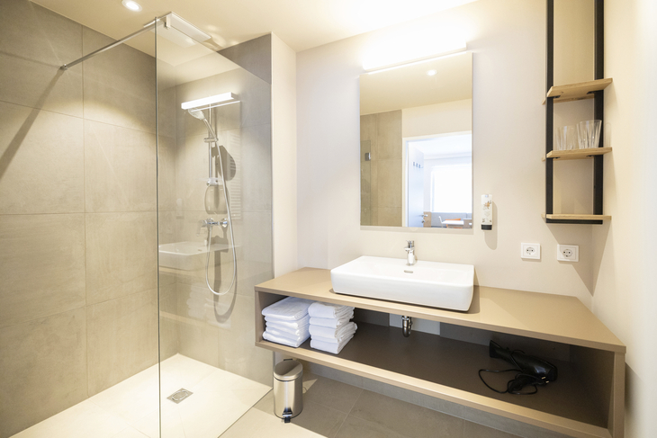 Modernes Badezimmer mit Dusche, Waschbecken und Spiegel.