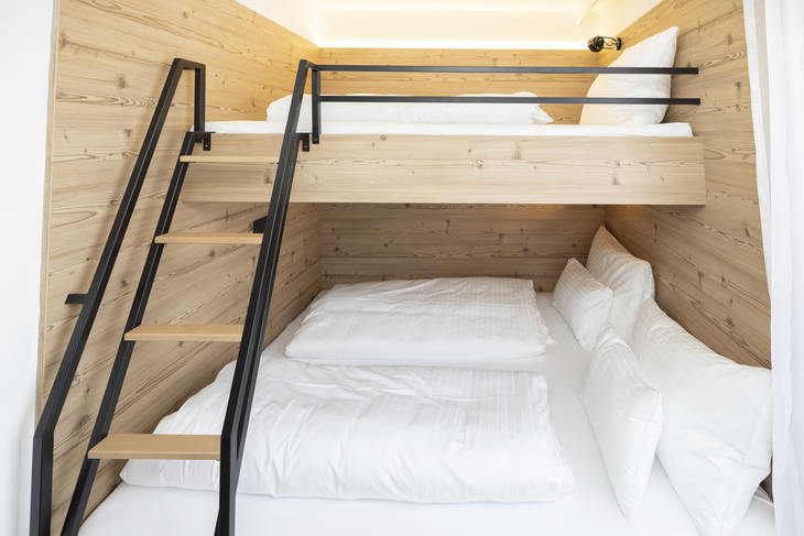 Stockbett mit Holzverkleidung und weißen Bettlaken in einem modernen Schlafzimmer.