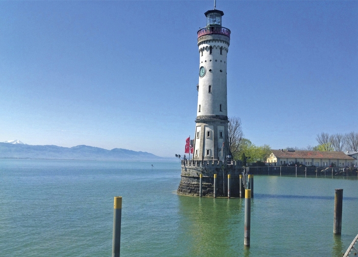 Leuchtturm auf dem Bodensee bei klarem Himmel und ruhigem Wasser.