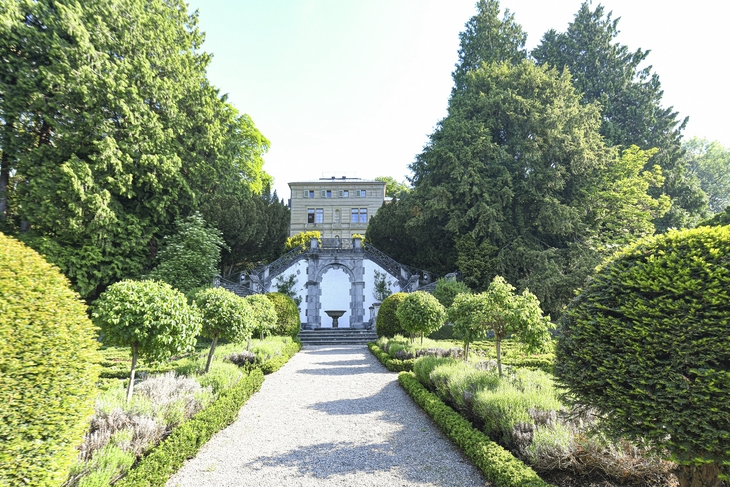 Villa inmitten eines gepflegten Parks mit auffälligen Hecken und Bäumen.