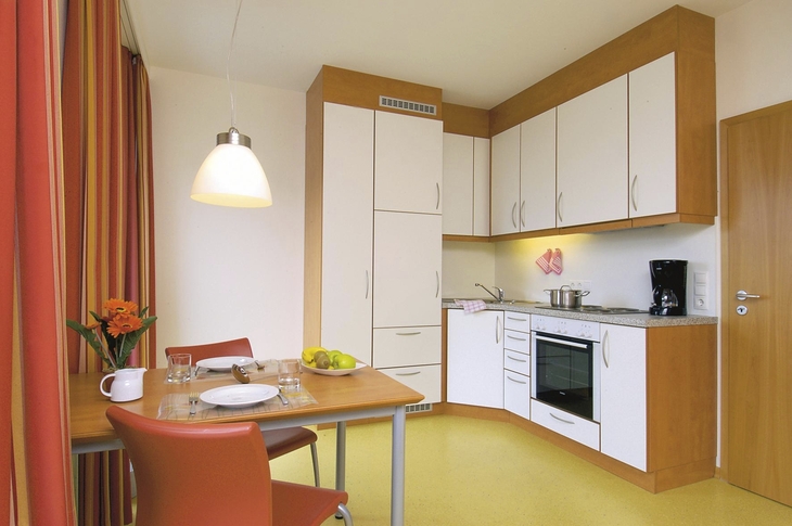 Moderne Küche mit Esstisch in einer Ferienwohnung, hell gestaltet mit weißen Möbeln.