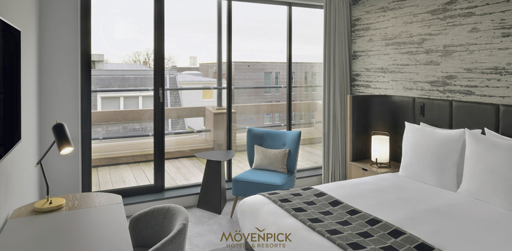Hotelzimmer mit Doppelbett, Sitzbereich und Fenster mit Stadtblick.