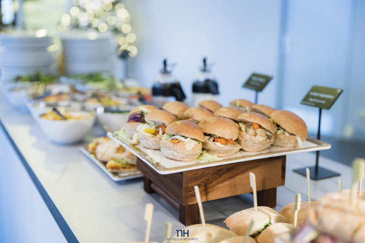 Buffet mit belegten Brötchen und Salaten auf einem Tisch.