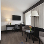 Ein modernes Hotelzimmer mit Schreibtisch, Fernseher und Sesseln.