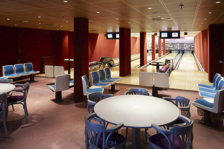 Bowlingbahn mit mehreren Bahnen und leeren Sitzbereichen.