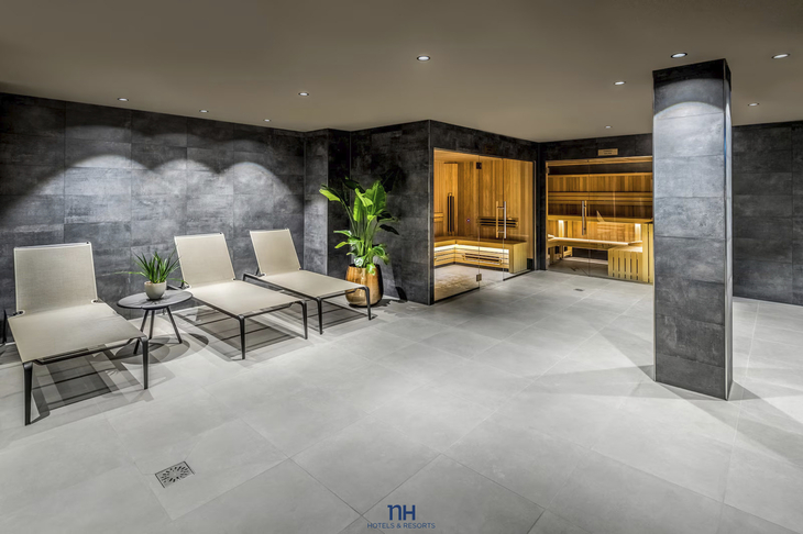 Wellnessbereich mit Liegestühlen und Sauna im Hintergrund.