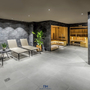 Wellnessbereich mit Liegestühlen und Sauna im Hintergrund.